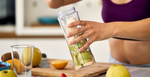 Woman filling the blender with fruits